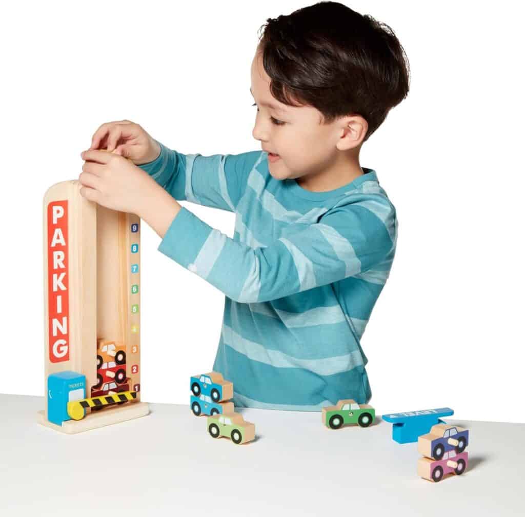 A young boy is playing with the Melissa & Doug Stack & Count Wooden Parking Garage With 10 Cars.