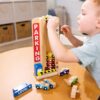 A young boy playing with a Melissa & Doug Stack & Count Wooden Parking Garage With 10 Cars at a table.