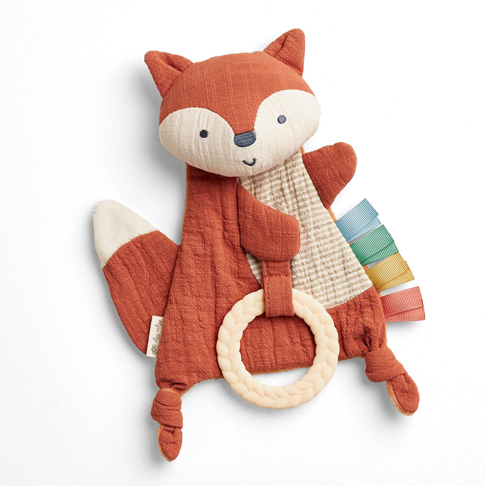 Plush toy fox with a textured ring, multicolored fabric tabs on its side, and a tag on the leg.