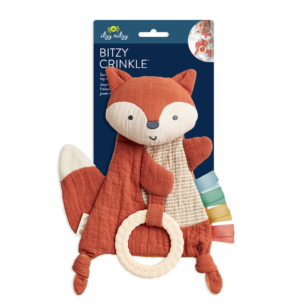 A soft, orange fox-shaped baby toy with a crinkly body, attached teether ring, and multi-colored fabric tabs. The packaging displays the name "Bitzy Crinkle" and the Itzy Ritzy brand logo.