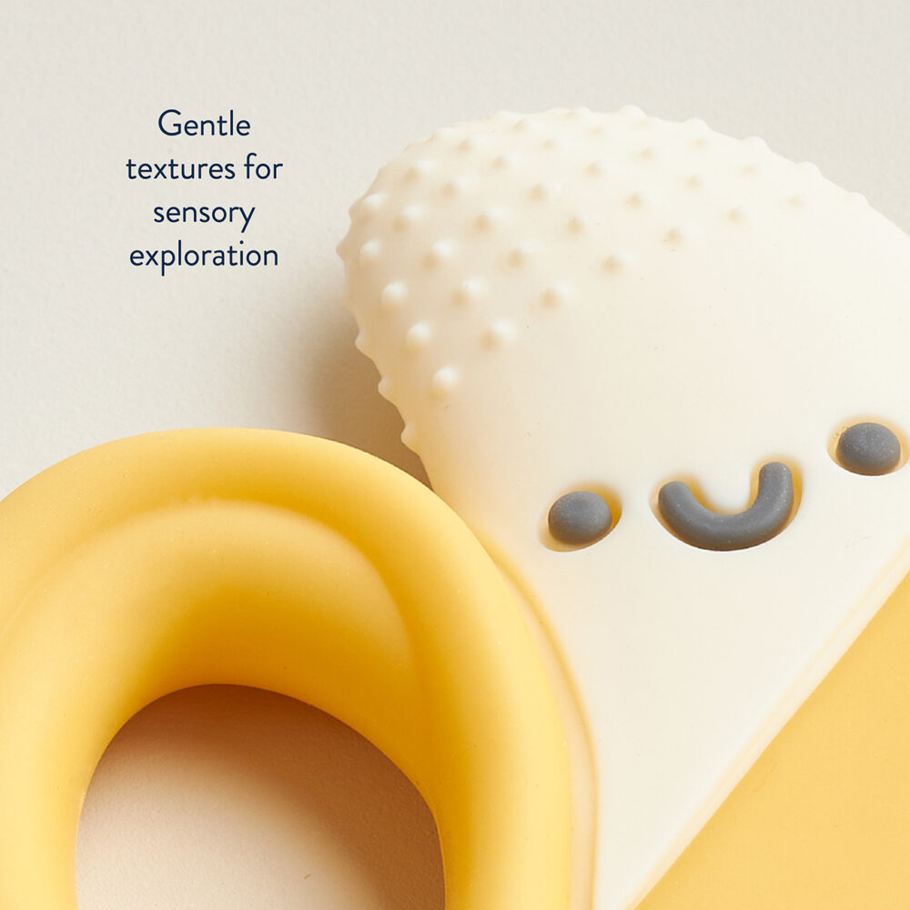 Close-up of the Itzy Ritzy Chew Crew Silicone Teether with Handles, showcasing its gentle textures and soft colors along with a smiley face, accompanied by text: "Gentle textures for sensory exploration.