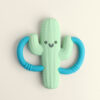 The Itzy Ritzy Chew Crew Silicone Teether with Handles features a green cactus shape adorned with blue circular handles on each side and a smiling face in the center.