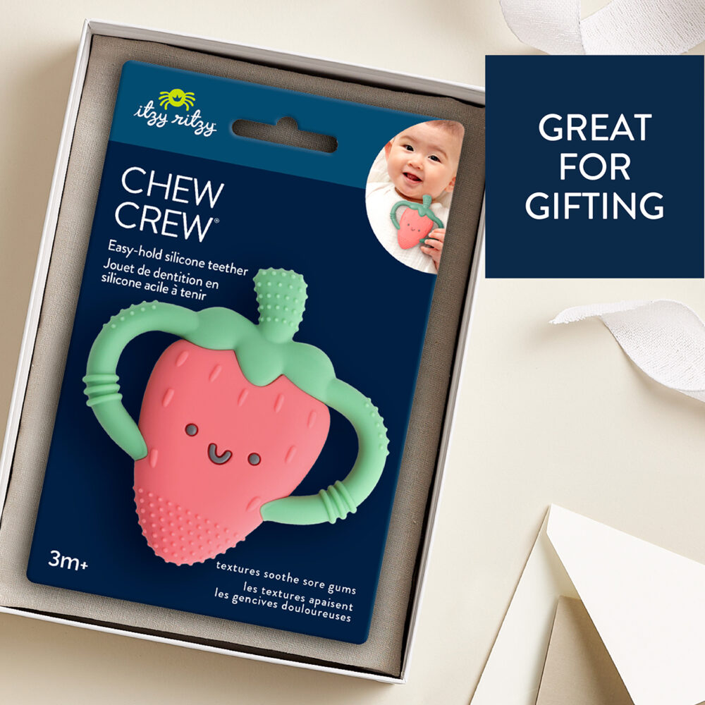 A boxed Itzy Ritzy Chew Crew Silicone Teether with Handles, designed for infants aged 3 months and up, features a strawberry shape. The packaging is adorned with text that reads "Chew Crew" and “Great for Gifting.”.