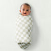 Baby wrapped in the Breastfeeding Boss, A Multitasking Must-Have for Nursing, Swaddling & More, lying on a white background.