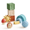 Assorted Itzy Ritzy Sensory Blocks 10-Piece Set including textured blocks, a sunny figure, a mushroom, a hedgehog, and a blue arch, all made of soft, colorful plastic.