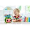 A smiling child is holding a green toy microphone while sitting next to a colorful toy with a smiling face. The child is wearing a striped shirt and is in a brightly lit indoor setting.