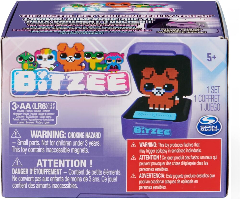 A Spin Master Bitzee Interactive Toy Digital Pet package showing a cute pixelated bear character on the LCD screen, suitable for ages 5+. Includes choking hazard warning and requires 3 AA batteries.