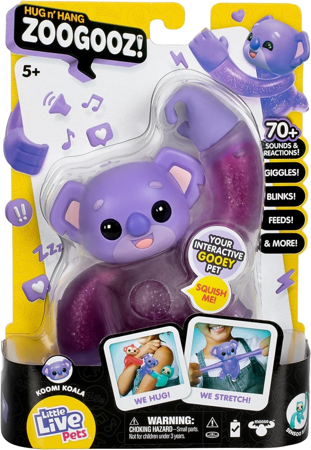 A packaged toy labeled "Hug n' Hang Zoogooz!" featuring a purple koala named Koomi Koala. It advertises over 70 sounds and reactions, including giggles and blinks. Suitable for ages 5 and up.