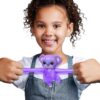 A young girl smiles while holding a purple, stretchy toy shaped like a monkey with both hands.