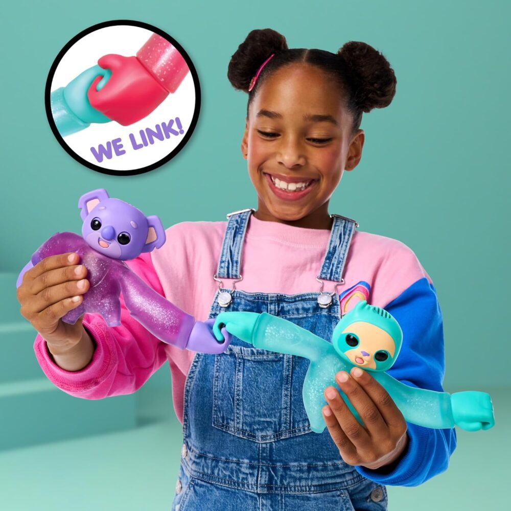 A child in a pink shirt and denim overalls is playing with two colorful toy animals that link hands. A close-up inset shows how the toys connect, with text that reads "WE LINK!.