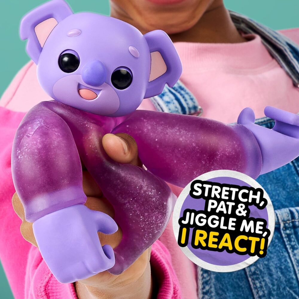 A person holds a purple koala toy with text beside it saying, "Stretch, pat & jiggle me, I react!" The toy has a smiling face and extended limbs.