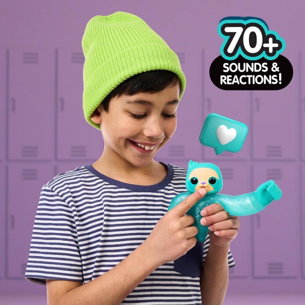 A young boy wearing a green beanie and striped shirt holds a blue interactive toy sloth. Text reads "70+ sounds & reactions!" with a heart icon. Lockers are visible in the background.