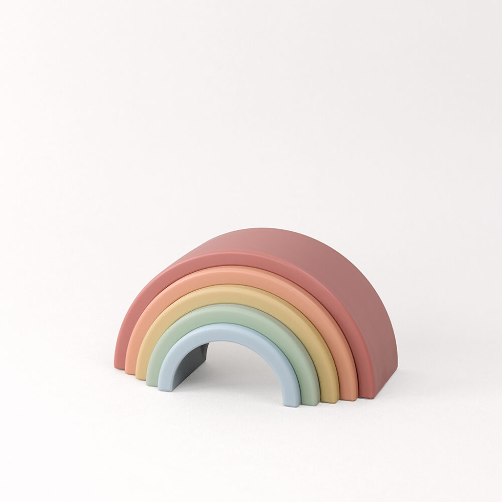 A stack of colorful wooden rainbow arches arranged from largest to smallest against a plain white background.