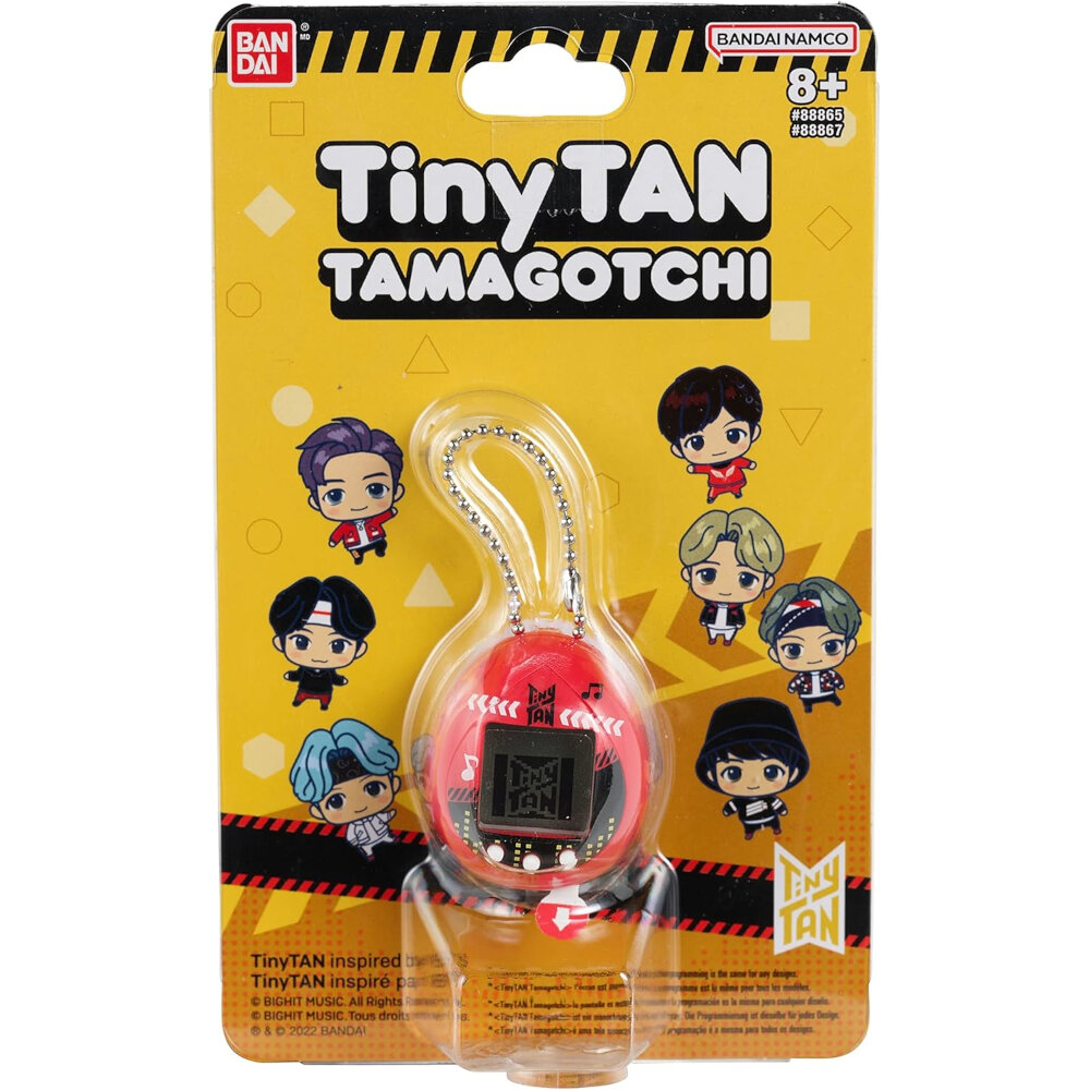 Image of a TinyTAN Tamagotchi toy in its original packaging. The packaging is yellow with cartoon characters and branding details from Bandai Namco. Suitable for ages 8 and up.