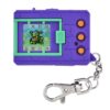 A purple and green virtual pet device with three orange buttons and a keychain attachment. The screen displays a pixelated creature.