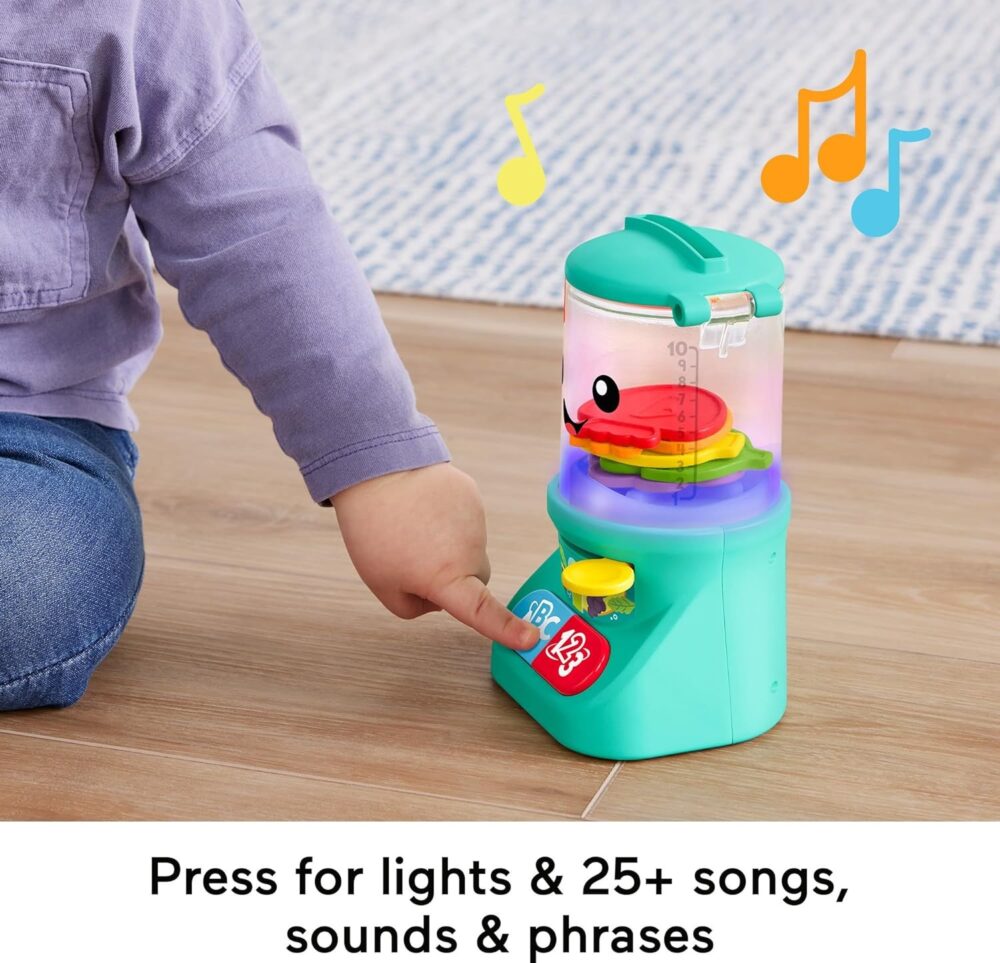 A child presses a button on the Fisher-Price Laugh & Learn Baby & Toddler Toy Counting & Colors to activate lights and sounds. The toy features colorful music notes and a red fish inside. Text at the bottom reads, "Press for lights & 25+ songs, sounds & phrases.