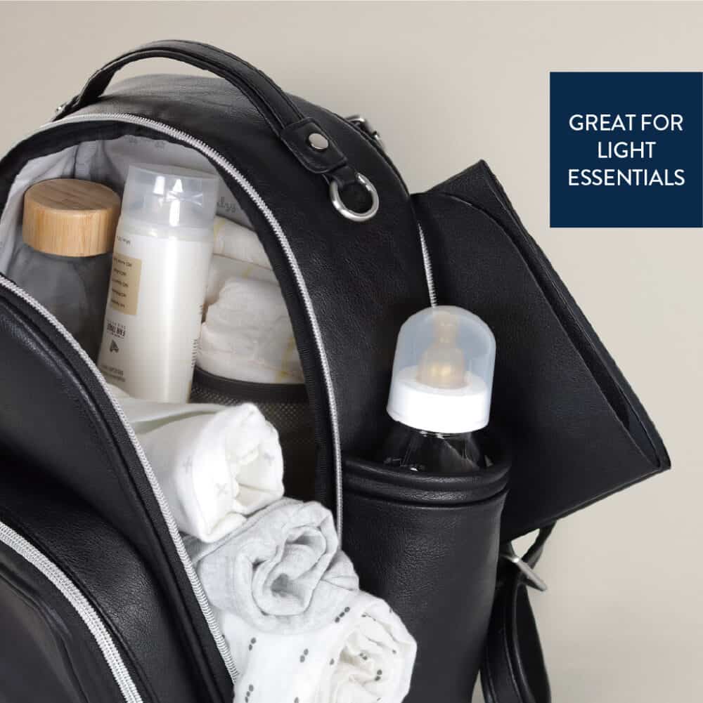 A black backpack is shown with its main compartment open, revealing a baby bottle, rolled clothes, and various small containers. A side pocket holds another baby bottle. Text reads "GREAT FOR LIGHT ESSENTIALS.