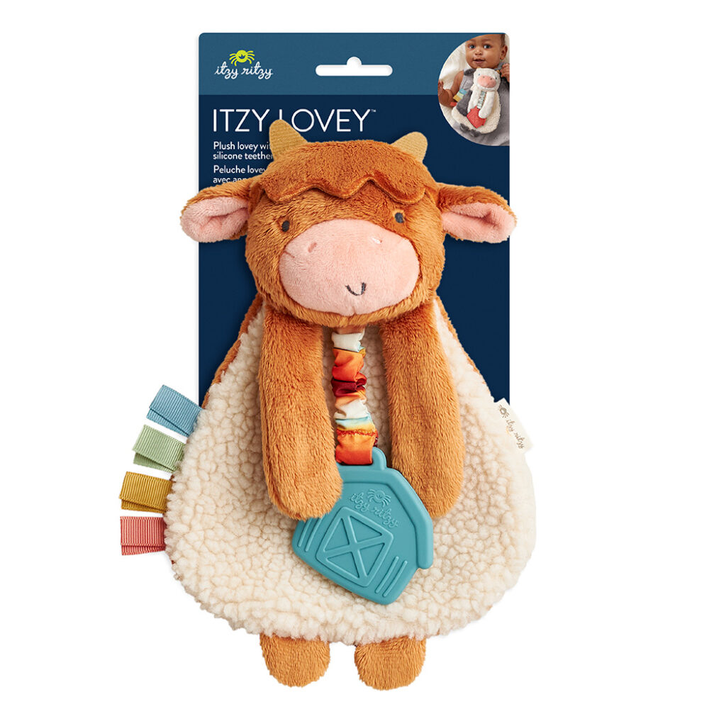 A plush cow baby toy with a silicone teether and multiple colored tags attached. The toy is packaged on a card that includes a small image of a baby holding the toy.