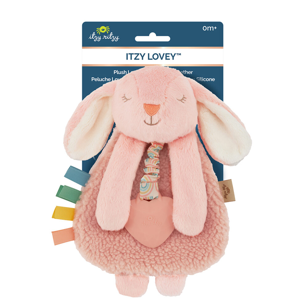 A soft pink plush toy resembling a bunny, labeled "Itzy Lovey" by Itzy Ritzy, with a teething ring and attached colorful fabric tags. Suitable for infants.