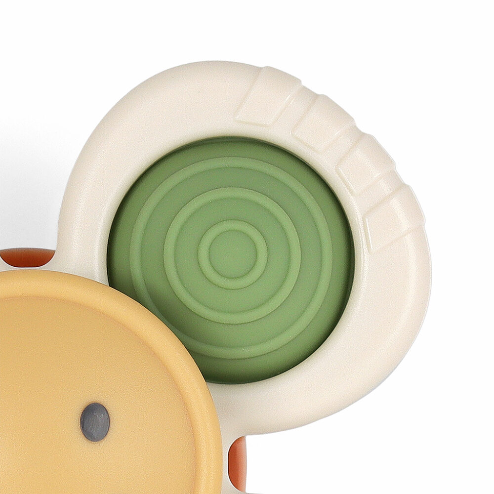 Close-up of a beige, green, and yellow plastic toy with textured details and circular patterns.