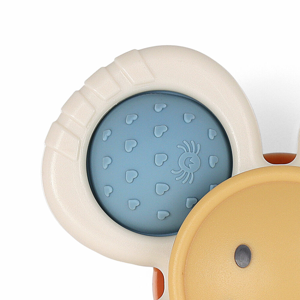 A close-up of a baby teething toy featuring a round, blue textured section with heart patterns and a small spider icon, set against a white and yellow background.